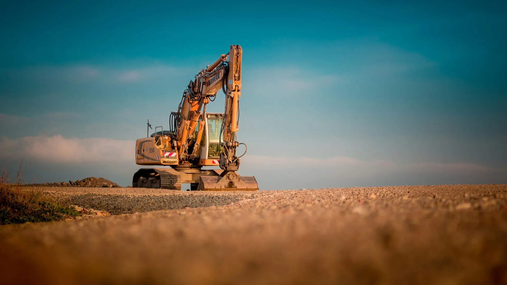 Yellow Liebherr crawler excavator parked on a construction site under a blue sky