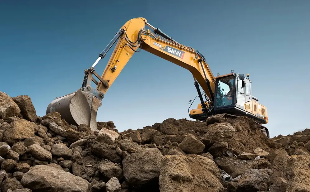 Yellow SANY crawler excavator on a rocky construction site under a blue sky